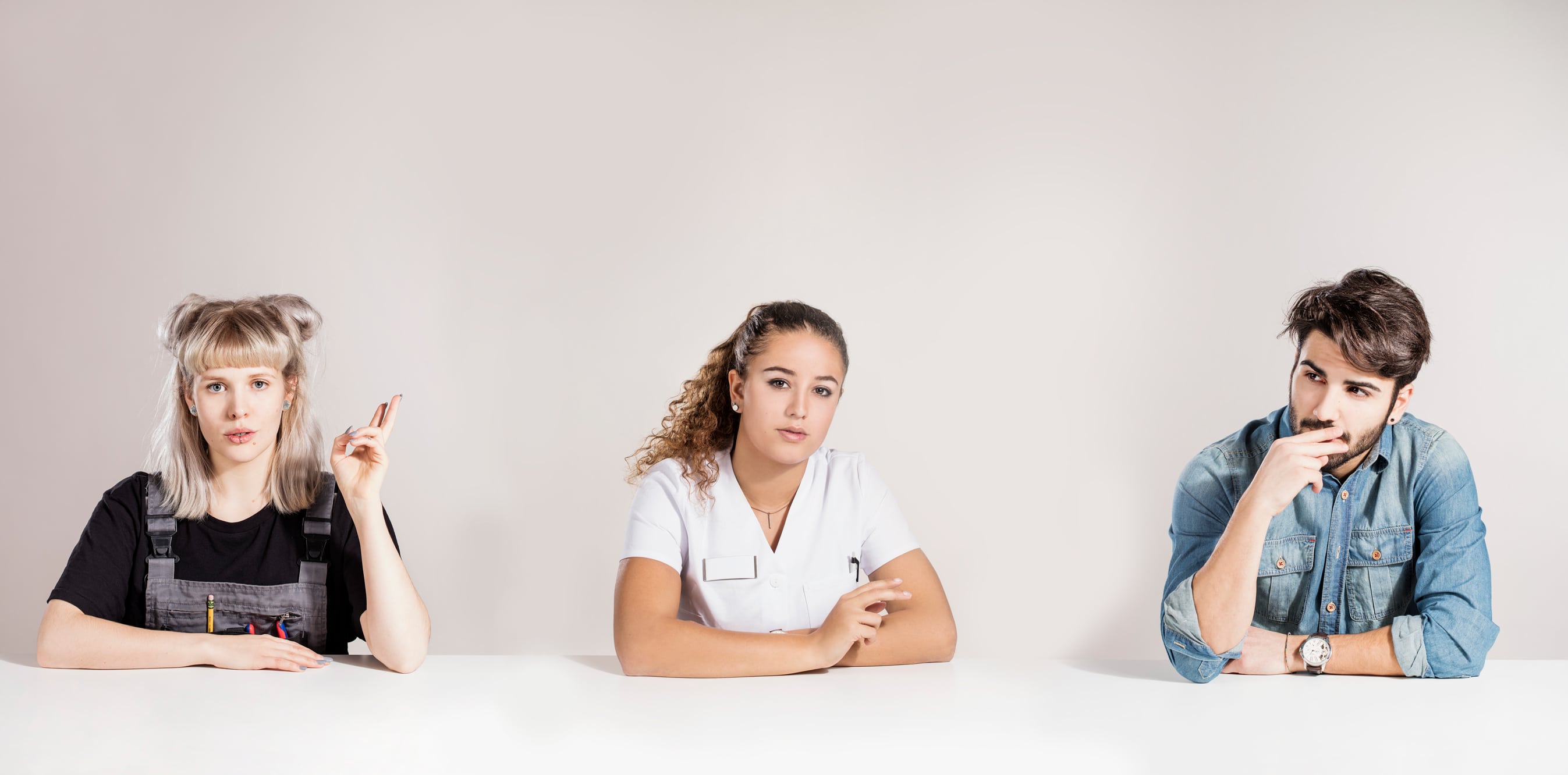 Drei junge Personen sitzen nebeneinander und halten ihre Finger als würden sie eine Zigarette halten.